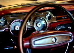 SCP_11 classic mustang steering wheel focus on the background a dashboard in burgundy and dark brown wood grain combination surrounding the speedometer, fuel gauge air vents and lighter